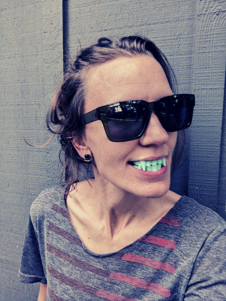 Lore Simone wearing sunglasses and plastic fangs.